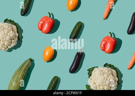Muster mit verschiedenen Gemüse auf türkisblauem Hintergrund. Gemüse abstrakter Hintergrund. Paprika, Tomaten, Gurken, Karotten, Kürbis, Caulif Stockfoto