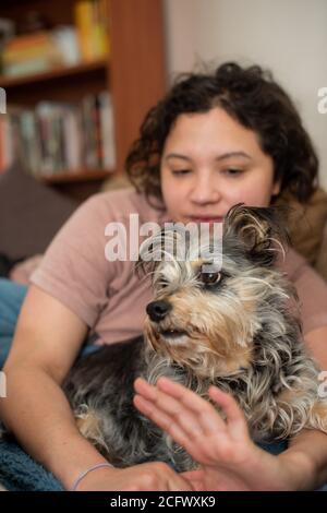 Vertikales Porträt der Frau und ihres Hundes, die allein Zeit zu Hause verbringen. Stockfoto