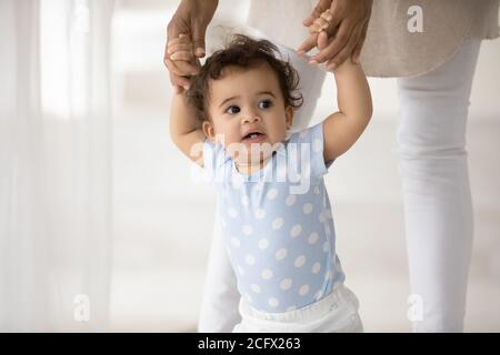 Neugierige kleine gemischte Rennen Kind lernen zu Fuß mit biracial Mutter. Stockfoto