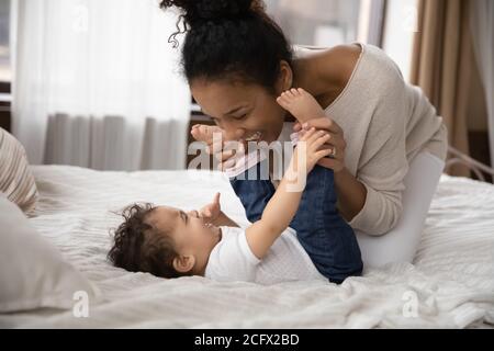 Lächelnd liebevolle biracial Mutter Spaß mit Kind im Schlafzimmer. Stockfoto