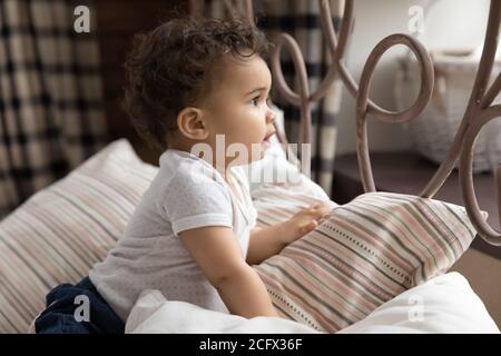 Liebenswert kleine afroamerikanische Baby Junge oder Mädchen kriechen auf dem Bett. Stockfoto