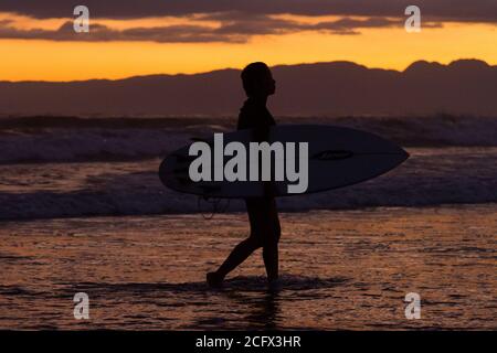 Surfer bei Sonnenuntergang an einem Strand in Enoshima, Kanagawa, Japan. Stockfoto