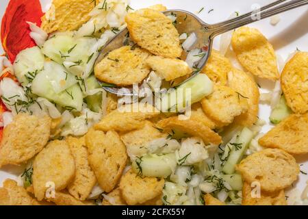 Eine Nahaufnahme von Crouton und Gurkensalat in einem weißen porzellanplatte und Tischlöffel darin. Stockfoto