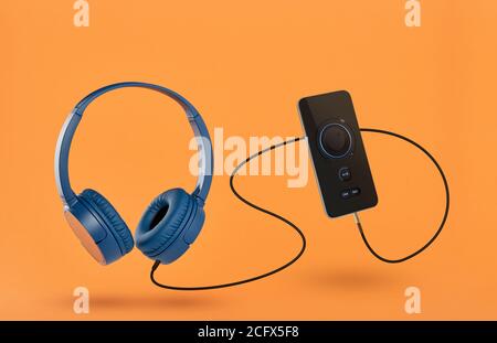 Kopfhörer und Mobiltelefon auf orangefarbenem Hintergrund Stockfoto