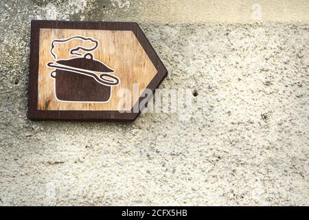 Ein Holzschild zeigt auf der rechten Seite ein Restaurant an