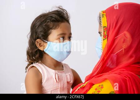 Mutter und Tochter tragen Maske und schauen sich an Stockfoto
