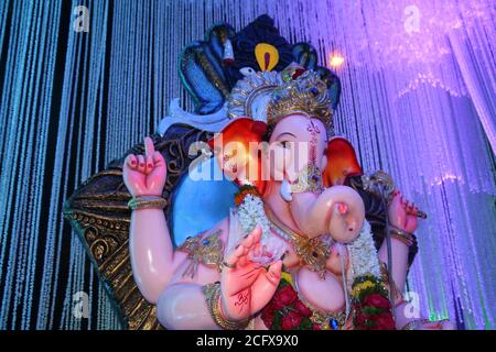 Ganesh Idol mit schönen weißen Dekoration Hintergrund. Nahaufnahme von der Hand in Richtung Gesicht. Stockfoto