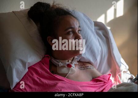 Sacramento, Kalifornien, USA. Februar 2020. FELICIA BRENT-VELASQUEZ, 18, sitzt im Februar in einem Krankenhausbett, während sie sich zu Hause von einem Autounfall erholt, bei dem sie eine Quadriplegikerin hinterlassen hat. Vor dem Unfall, als sie eine Bewohnerin des Kinderempfangsheims von Sacramento war, sagte sie, dass sie nur die Sicherheitskräfte bitten müsse, das Tor zu öffnen und sie würde direkt aus dem Haus gehen und ins AWOL gehen. Sie hat ein Tattoo auf ihrer Schulter für einen Jungen, mit dem sie in einer Beziehung war und der in Southside Park starb. Seine eingeschrieben mit einem Leben Puls schlagen, seinen Tag des Vergehens, und die Worte "bis wir wieder für immer in m treffen Stockfoto