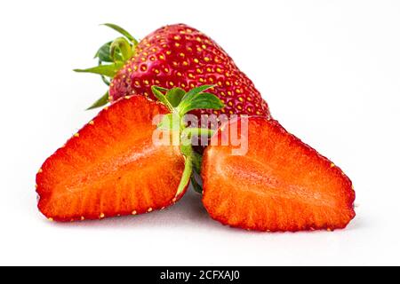 Zwei Erdbeeren auf weißem Hintergrund eine Erdbeere ganz die andere ist in zwei Hälften geschnitten Stockfoto