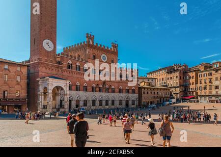 Schöner Panoramablick auf das berühmte Rathaus Palazzo Pubblico, ein beliebter Touristenort auf dem historischen Hauptplatz Piazza del Campo an einem sonnigen Tag... Stockfoto