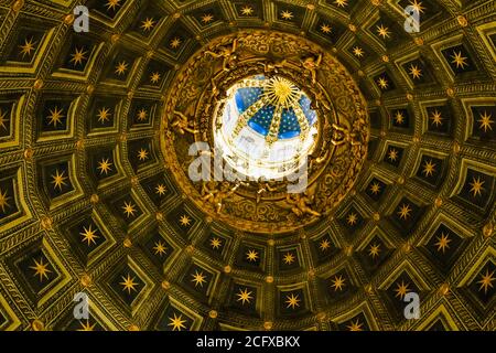 Nahaufnahme des Innenraums der sechseckigen Kuppel des Duomo di Siena. Es ist mit Berninis vergoldeter Laterne gekrönt, wie eine goldene Sonne. Die Trompe l'oeil... Stockfoto