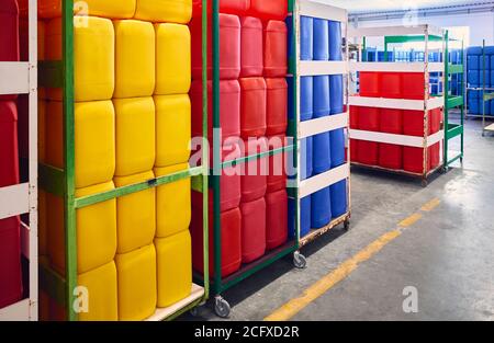 Rote, gelbe und blaue Kunststoffbehälter für Chemikalien in einem Lager. Stockfoto