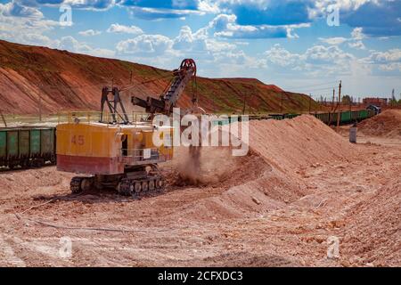 Aluminiumerz Bergbau und Transport. Bauxit-Tonerde-Tagebau. Verladung von Erz mit Elektrobagger in Trichterwagen Zug. Stockfoto