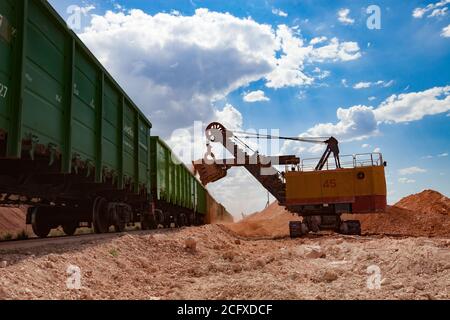 Aluminiumerz Bergbau und Transport. Bauxitton. Tagebau. Verladung eines Erzes mit Elektrobagger in Trichterwagen Zug. Stockfoto