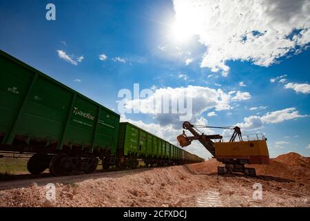 Aluminiumerz Bergbau und Transport. Bauxit Tonerde Tagebau. Verladung eines Erzes mit Elektrobagger in Trichterwagen Zug. Stockfoto