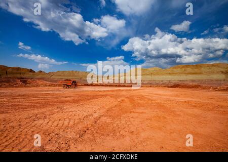 Steinbruch aus Bauxit. Aluminiumerz Bergbau und Transport. Tagebau. Orange Hitachi Steinbruch Muldenkipper mit orangefarbenem Ton. Stockfoto