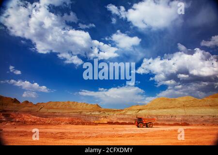 Aluminiumerz Bergbau und Transport. Steinbruch aus Bauxit. Tagebau. Orange Hitachi Steinbruch Kipper. Am blauen Himmel mit Wolken. Stockfoto