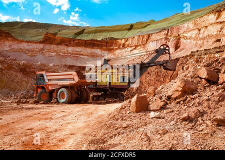 Bagger belädt Erz zu Hitachi Steinbruch Muldenkipper. Aluminiumerz Bergbau und Transport. Bauxit Clay Tagebau. Stockfoto