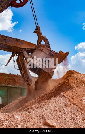 Aluminiumerz-Steinbruch. Bauxit-Tonerde-Tagebau. Beladung von Erz auf Eisenbahntrichter mit Bagger. Nahaufnahme Baggerbecher und Stahlkabel. Stockfoto