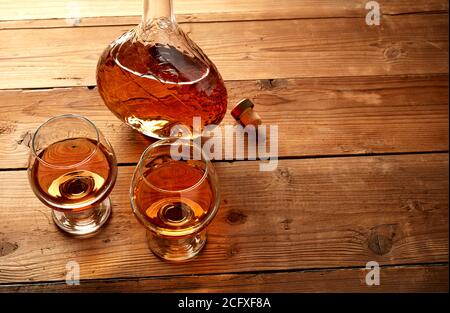 Gläser und eine Flasche Cognac auf einem alten Holztisch Stockfoto