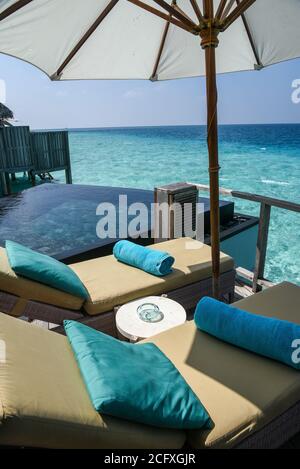 Ein Paar gepolsterte Sonnenliegen und Handtücher befinden sich neben dem Tauchbecken der privaten Terrasse einer Villa in einem Luxusresort auf den Malediven. Stockfoto