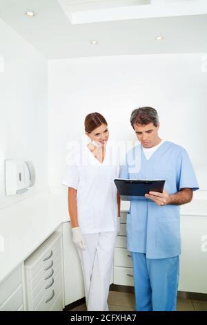 Arzt neben Krankenschwester prüft Krankenakte auf Zwischenablage Stockfoto