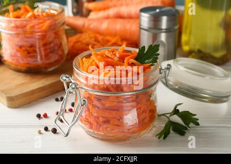 Komposition mit leckerem Karottensalat auf weißem Holzhintergrund. Koreanische Karotte Stockfoto