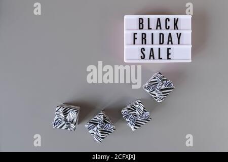 Black Friday Sale Text auf weißem Leuchtkasten und Geschenk-Boxen auf grauem Hintergrund. Schwarzes Freitagsschild mit Kopierplatz. Thanksgiving Werbeaktion Stockfoto
