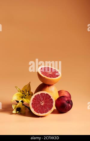 Stillleben mit Früchten und Orange Töne, mit Orangen, Granatapfel und Pfirsiche auf einem orangen Hintergrund. Stockfoto