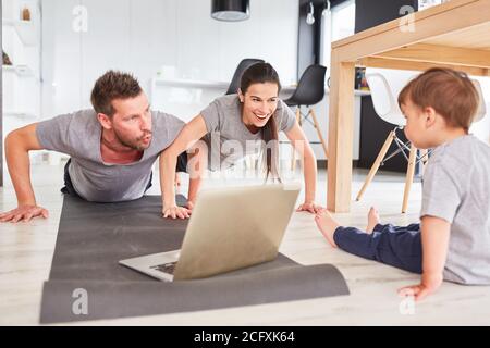 Sportliche Eltern treiben Sport vor dem Laptop Während des Streamings von Videos Stockfoto