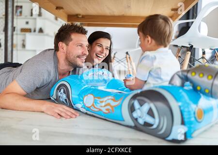 Lachende Eltern spielen mit ihrem Sohn im aufblasbaren Kinderzimmer Auto als Schlauchboot aus Gummi Stockfoto