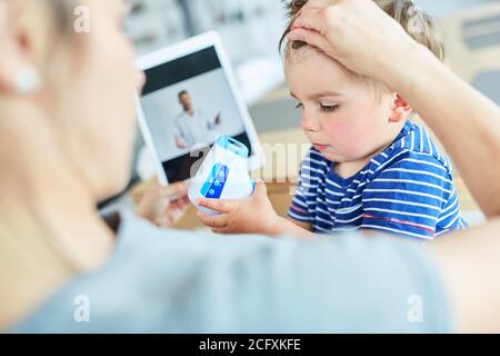 Mutter und krankes Kind messen Fieber im Internet Beratung im Video-Chat Stockfoto