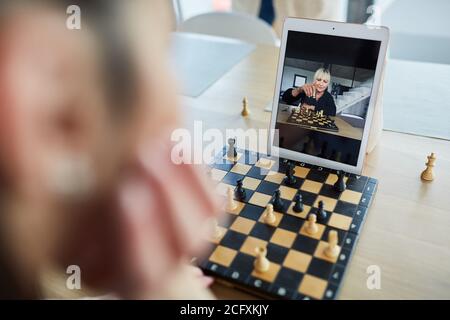 Frau spielt Schach mit einem Freund in Video-Chat online Auf dem Tablet-Computer Stockfoto
