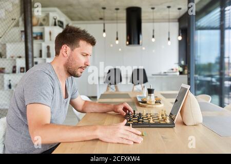 Junger Mann spielt Schach in Video-Chat online zu Hause Im Wohnzimmer Stockfoto