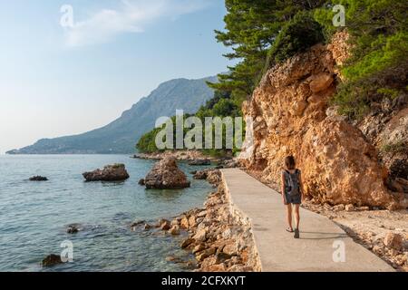 Unbekannte Frau geht an der touristischen Route entlang der Adriaküste in Makarska riviera, Kroatien Stockfoto