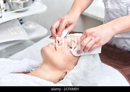 Kosmetikerin reinigt das Gesicht mit Servietten. Frau bei Spa-Verfahren Stockfoto