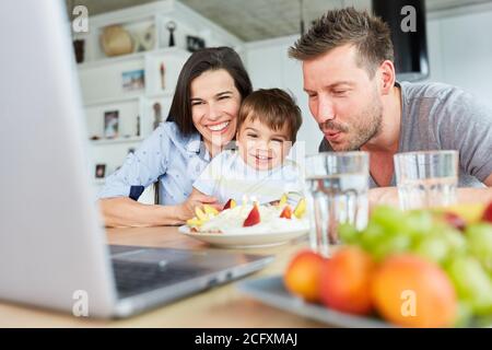 Familie mit Kind bläst Kerzen auf dem Kuchen hinein Video-Chat für einen Geburtstag Stockfoto