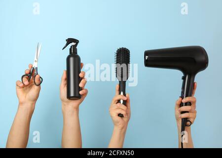 Weibliche und männliche Hände halten Friseurwerkzeuge auf blauem Hintergrund Stockfoto