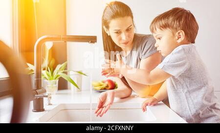 Das Kind lernt, sich mit der Mutter am Waschbecken die Hände zu waschen In der Küche als Hygienehandard Stockfoto