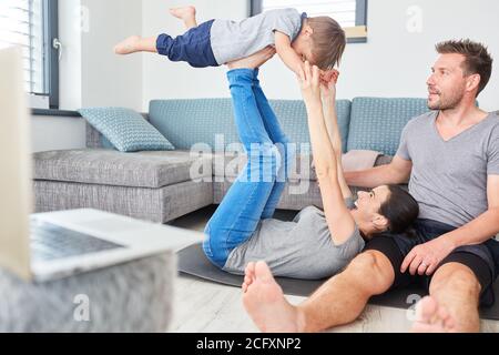 Eltern spielen mit Kleinkind im Wohnzimmer, während sie Videos streamen Auf einem Laptop-PC Stockfoto