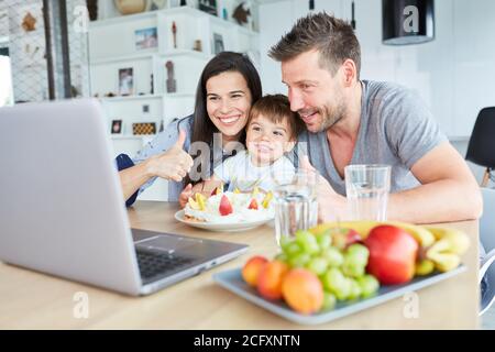 Familie feiert Geburtstag mit Kind und isst Kuchen auf Laptop Computer Stockfoto