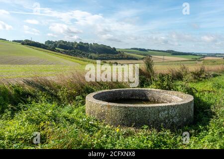 Landschaft Ackerland Landschaft im Norden Wessex Downs AONB bei Wexcombe, Wiltshire, UK, mit einem ungewöhnlichen kreisförmigen Wassertrog im Vordergrund Stockfoto