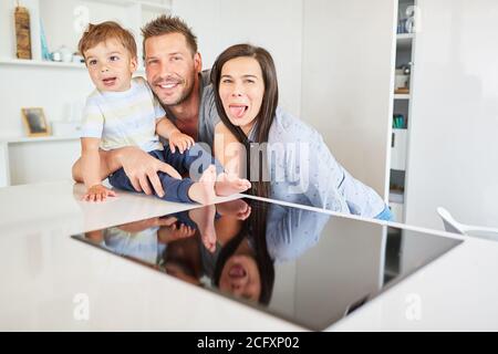 Glückliche Eltern, die herumtollten und mit ihrem Sohn Unfug machten In der Küche Stockfoto