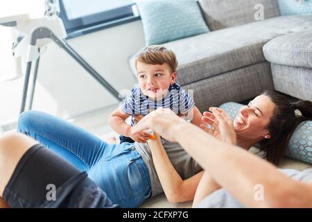 Mutter und Kind kuscheln und spielen zusammen auf dem Boden Im Wohnzimmer Stockfoto