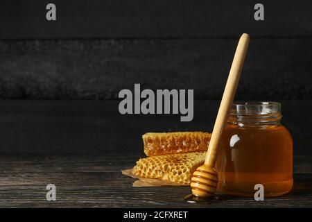 Waben, Glas mit Honig und Dipper auf Holzgrund Stockfoto