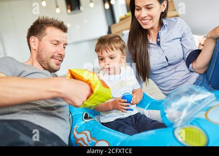 Eltern spielen mit Kleinkind im Beiboot als Auto Zuhause im Wohnzimmer Stockfoto