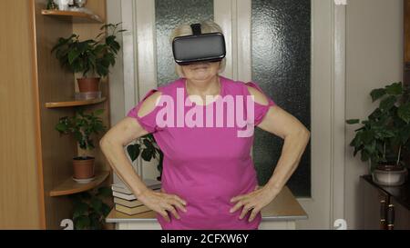 Senior Großmutter in virtuellen Headset-Brille beobachten 3D-Video in VR-Helm und Training Training zu Hause und Indoor-Training. Aktiv gesund Lifestyle sportliche alte Frau in VR-Brille spielen Stockfoto