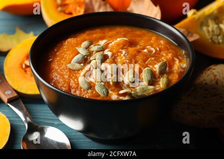 Holztisch mit Kürbissuppe und Samen im Nahaufnahme, eine gemütliche Herbstküchenszene Stockfoto