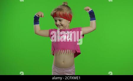 Kleine kaukasische Mädchen in rosa Sportbekleidung macht Fitness-Turner zu Hause Übungen, zeigt Muskeln. Workout für Kinder. Junge sportliche Kind in Sportanzug Trainingsbox, zeigt Faust Kampf. Chroma-Taste Stockfoto