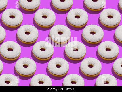 Leckere Donuts mit weißer zuckerhaltiger Verglasung und über Neon streut Violetter Hintergrund Stockfoto